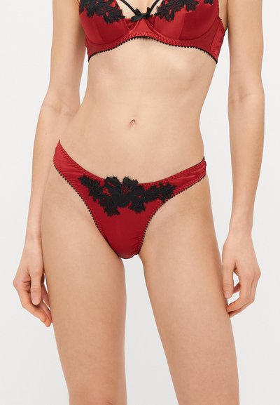 Ensemble de lingerie en satin rouge avec des accents en dentelle florale noire et des détails en ruban, avec un design ajusté et un bord décoratif.