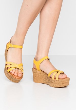 Yellow wedge sandals with braided strap design, cork platform, and adjustable ankle buckle. Smooth texture with open toe.