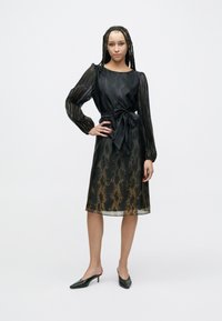 Schwarzes Kleid mit glänzendem, strukturiertem Finish und langen, durchsichtigen Ärmeln; verfügt über eine taillierte Passform mit Gürtel und einen Farbverlauf mit Schlangenprint in goldenen Akzenten.