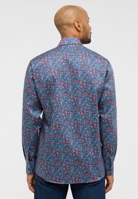 Langarmshirt van marineblauwe stof met een bloemenpatroon met rode en groene accenten. Gekraagd, slim-fit ontwerp met knoopsluiting bij de manchetten.