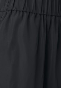 Tissu noir à texture lisse avec un élastique froncé à la taille. Le matériau semble léger et légèrement réfléchissant.