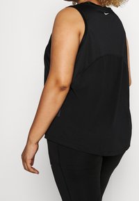 Černý sportovní tílko s kulatým výstřihem, volným střihem a síťovanými panely na zadní straně. Obsahuje malé logo v blízkosti límce.