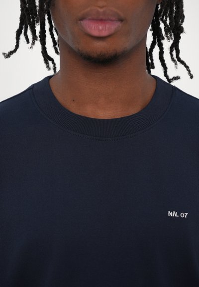 Sweatshirt marine avec col côtelé, arborant un petit logo blanc "NN. 07" sur la poitrine, confectionné en tissu coton doux.