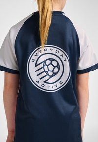 Mörkblå sporttröja med korta vita ärmar, med en cirkulär logotyp som har en fotboll och texten "EVERYDAY ACTIVE" på baksidan.