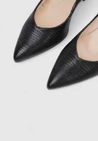 Bailarinas negras de punta afilada con un acabado texturizado con relieve de cocodrilo, que presentan un diseño de corte bajo y un interior suave. Estilo elegante y minimalista.