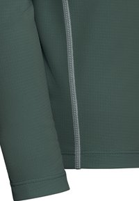 Haut sportif à manches longues vert foncé avec tissu texturé, coutures flatlock et une fine couture grise contrastante le long du côté.