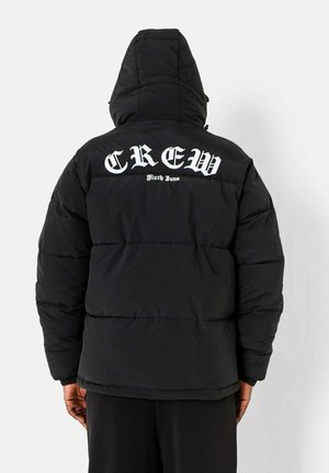 Doudoune noire avec capuche, dotée d'un grand texte blanc "CREW" et "Sixty June" dans le haut du dos, texture matelassée et coupe décontractée.