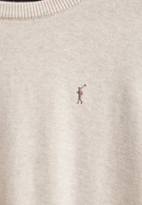 Beżowy sweter dzianinowy z prążkowanym dekoltem i małym brązowym haftowanym logo golfa po lewej stronie klatki piersiowej. Gładka faktura i swobodny design.