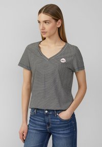 Gestreepte zwart-witte T-shirt met korte mouwen en V-hals, met een klein roze grafisch detail op de borst, gecombineerd met blauwe denim jeans.