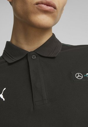 Czarna koszulka polo z teksturowanej tkaniny, z kołnierzykiem zapinanym na guziki, turkusowymi stębnowaniami i logo Mercedesa na piersi.