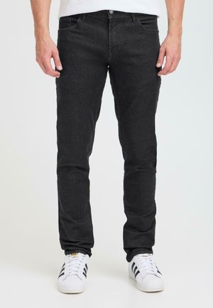 Mustad teksased,slim fit lõikega, koos viie taskuga, nööbi ja tõmblukuga, ning peene tekstuuriga. Kandmisel valged spordijalatsid.