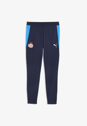 Granatowe spodnie sportowe z jasnoniebieskimi bocznymi panelami, herbem klubu piłkarskiego PSV po lewej oraz białym logo Puma na prawej udzie.