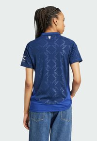 Maillot de sport bleu marine avec des motifs géométriques, manches courtes, col standard et accents en mesh pour la respirabilité. Vue arrière affichée.