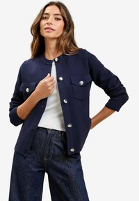 Námořnický cardigan na knoflíky s dvěma předními kapsami na klopu, vyrobený z měkké tkaniny, s stříbrnými knoflíky a kulatým výstřihem.