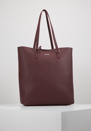 Donkerbruine leren tas met structuur, dubbele schouderbanden en een klein zilverkleurig "HUGO"-logo aan de voorkant.