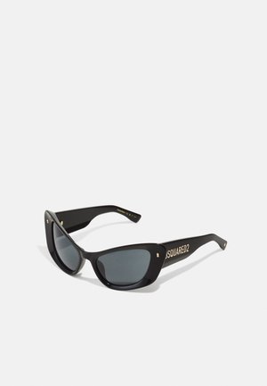 Lunettes de soleil noires en forme d'œil de chat, avec des verres gris et des accents dorés sur les branches portant le nom de la marque "DSQUARED2." Texture en plastique lisse.