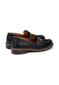 Mocasines de cuero negro con acabado texturizado, acento de ante marrón en la parte superior y un tacón bajo y apilado. Detalle de costura ligera en los lados.