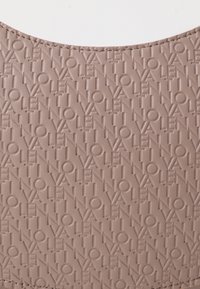 Matériau beige en relief présentant un motif de texte répété "VALENTINO". Texture lisse avec un design aux bords arrondis. Aucune autre détail présente.