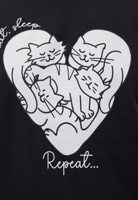 Schwarzes T-Shirt mit einer weißen Illustration von vier Katzen, die zu einer Herzform zusammengerollt sind, mit dem Text "Essen. Schlafen. Wiederholen..." darunter.