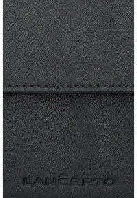 Czarny portfel z fakturowanej skóry z przeszywanym brzegiem i wytłoczonym logo. Kompaktowy design z gładką powierzchnią i subtelnymi detalami.