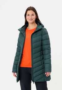 Groene pufferjas met capuchon, voorzien van een doorgestikt ontwerp en een ritssluiting aan de voorkant. Draagt een oranje top eronder, die warmte en bedekking biedt.