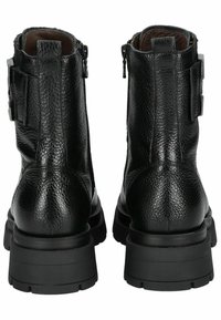 Bottines en cuir noir avec une finition texturée, dotées de zips sur les côtés et de semelles en caoutchouc épaisses. Accentuées par des boucles sur les côtés.