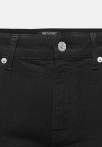 Lähikuva mustista denim-farkuista, jossa on metallinen nappi ja vyölenkit, ja sisällä näkyy "ONLY & SONS" -merkki.