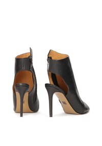 Chaussures à talons hauts en cuir noir avec un bout pointu, un dos ouvert, des découpes sur les côtés et une fermeture éclair au niveau du talon. Texture lisse.