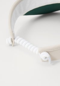 Adjustable headband made of soft beige fabric with a circular white elastic section, featuring a smooth texture and simple design.
