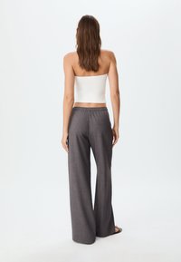 White strapless top paired with gray wide-leg pants featuring an elastic waist and subtle texture. Model facing away from the camera.