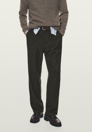 Pantalons en laine gris avec une coupe décontractée, associés à une chemise bleu clair et des chaussures en cuir marron. La texture est douce et texturée.