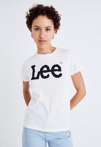 Vit bomull t-shirt med en stor svart "Lee" logotyp. Tröjan har en klassisk rund halsringning och korta ärmar.