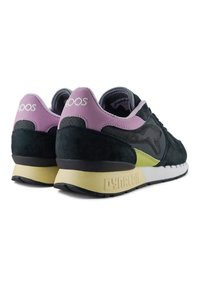 Sneaker in suede e rete nera con dettagli sul tallone in lavanda e pannello laterale verde lime. Presentano il marchio “DYNA-COL” sulla suola.