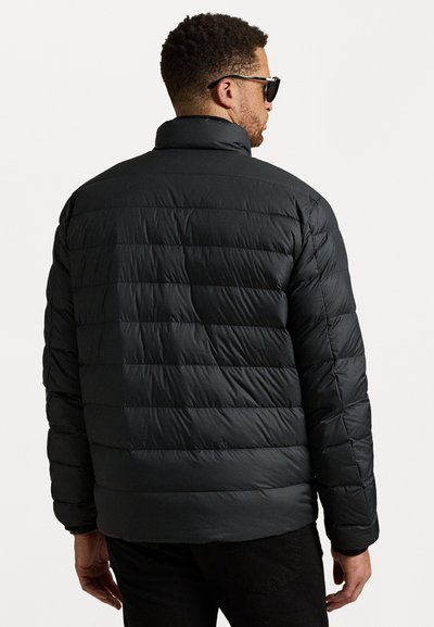 Man wearing black quilted puffer jacket and sunglasses, shown from the back against a plain white background.