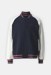 Chaqueta varsity en navy y crema con puños y cuello de canalé, que presenta botones y "TOMMY JEANS" bordado en rojo en el pecho.