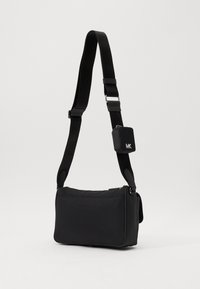 Borsa a tracolla nera realizzata in materiale morbido. Presenta una tracolla regolabile, accessori in argento e una piccola pochette attaccata con logo. Forma rettangolare.