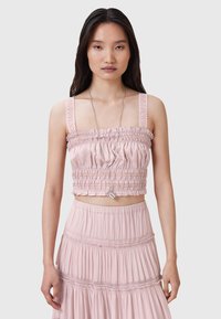Lys pink cropped top med rynket tekstur og blondedetaljer på stropperne, parret med en matchende lagdelt nederdel med elastisk talje.