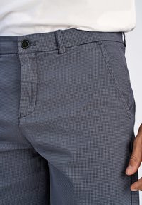 Pantaloni grigi con motivo e superficie testurizzata, dotati di tasca frontale, chiusura con bottone e design con passante per cintura.