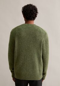 Πράσινο πουλόβερ με υφή κλέντ, διαθέτοντας στρογγυλή λαιμόκοψη και ριμπ μανσέτες και τελείωμα. Το ύφασμα έχει διακριτικά στίγματα κίτρινης απόχρωσης.