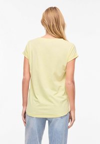 Ανοιχτό κίτρινο κοντομάνικο μπλουζάκι με στρογγυλή λαιμόκοψη, απαλή υφή και χαλαρή εφαρμογή, σε προβολή από πίσω. Φορεμένο με ανοιχτό μπλε τζιν.