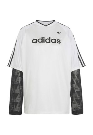 Camiseta blanca de manga larga de Adidas con mangas de malla negra, logotipo y texto de Adidas en negro en el pecho, y tres rayas negras en las mangas de los hombros.