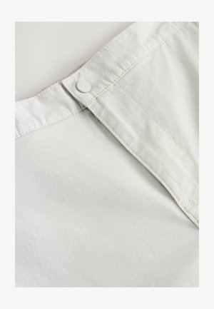 Bela bombažna tkanina z gumbom na pasu, ki se ponaša z diskretno teksturo in šiviljskim detajlom ob šivih.