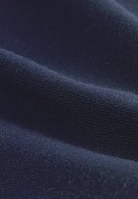 Tissu tricoté bleu marine avec une texture fine, présentant de douces plis et une légère duveteux. Le matériau semble extensible et lisse.