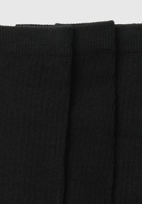 Calcetines negros de canalé con una superficie texturada, que cuentan con un puño reforzado y un acabado suave, adecuados para uso casual o formal.