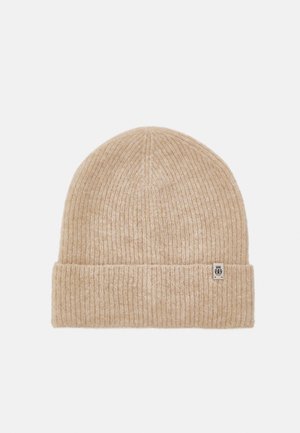 Beige ribbed knit beanie with a folded cuff and small logo tag. Soft texture with a tapered top, suitable for cold weather.
