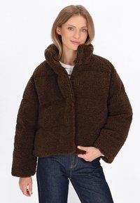 Braune, kuschelige, übergroße Jacke mit hohem Kragen und Reißverschluss vorne. Strukturierter Stoff und weite, umgeschlagene Ärmel.