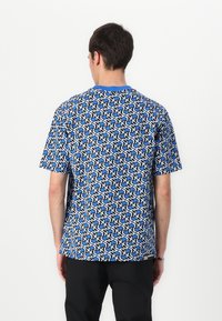 Blaues kurzärmliges T-Shirt mit einem geometrischen Schwarz-Weiß-Muster, Rundhalsausschnitt und einem schwarzen Logo-Detail am Saum.