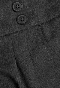 Tessuto grigio scuro con una texture liscia, con due bottoni neri e dettagli di cucitura visibili sulla vita.