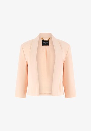 Hell pfirsichfarbener kurz geschnittener Blazer mit Schalkragen und dreiviertel Ärmeln, mit einem schwarzen Etikett und einer goldenen Kette im Nacken.