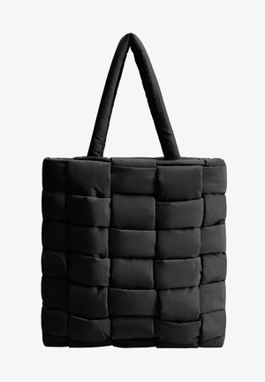 Sac cabas noir matelassé avec sections rectangulaires tissées et deux larges bretelles épaisses sur fond blanc.